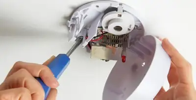 Certified technician wiring smoke detector during installation in San Jose, CA